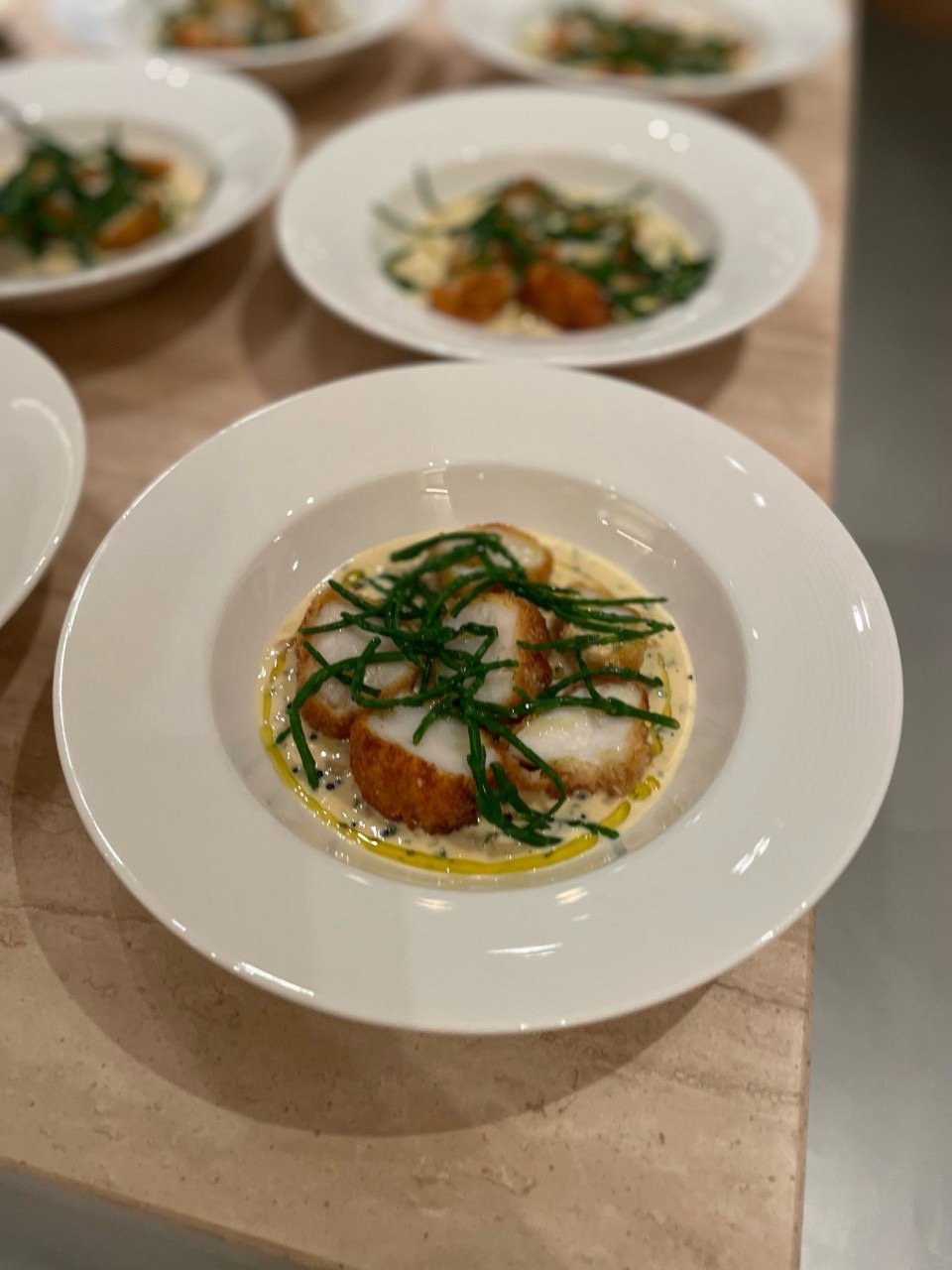 Vieiras fritas em profundidade com molho beurre blanc, caviar e salmão cru, acompanhadas de algas marinhas e óleo de endro — preparado para jogador profissional de futebol.